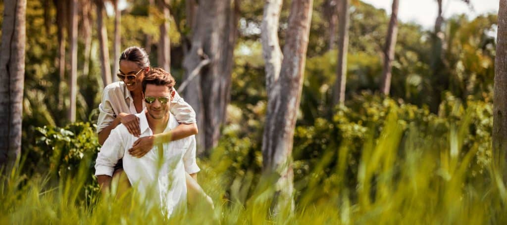 man carries woman on back during a walk in field