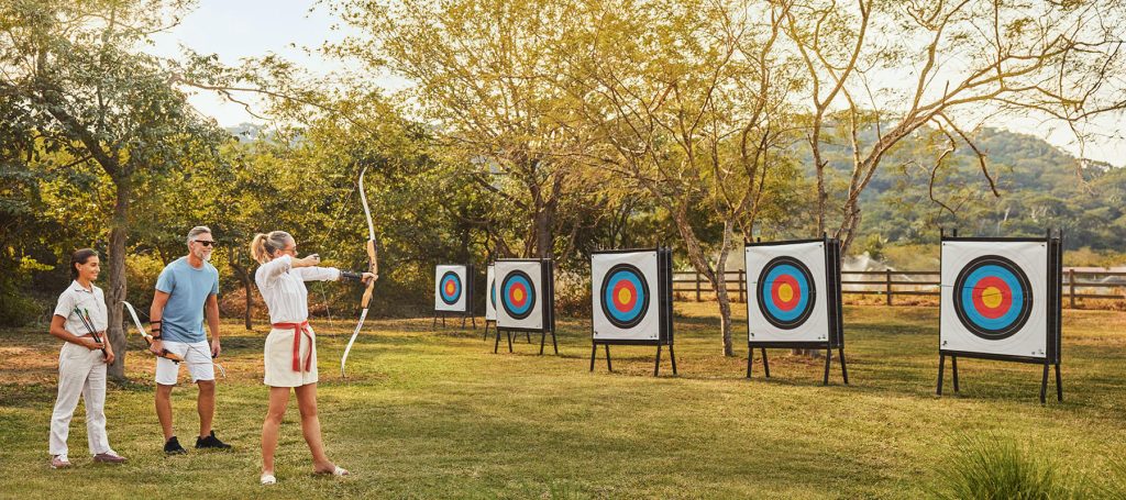 couples aims at target in a field doing archery
