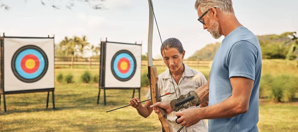 instructor shows person how to load arrow in archery