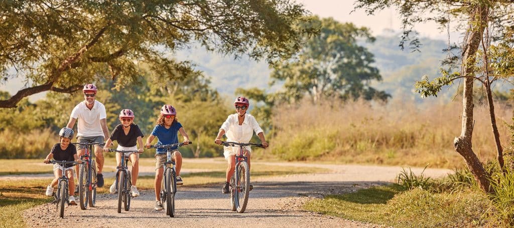 family with kids bikes along flat fields of mandarina