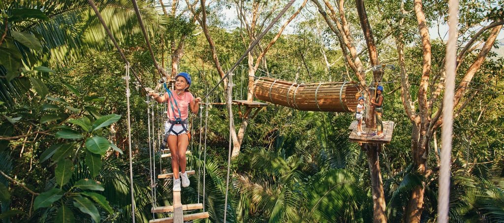 girl walks along hanging bridge steps in jungle