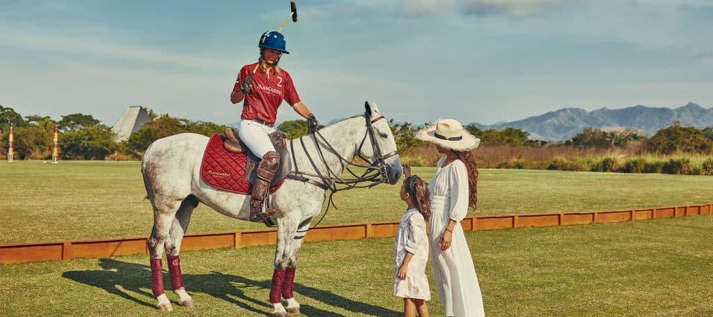 polo player in uniform on horse talks with spectators
