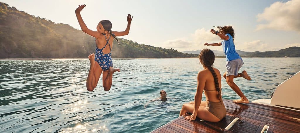 kids jump off boat into ocean as mom watches