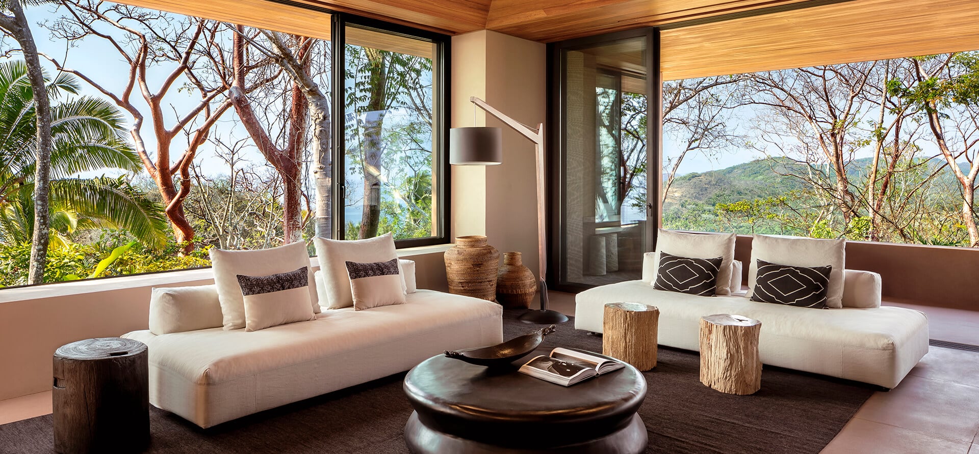 modern living room in mandarina with window walls and jungle views